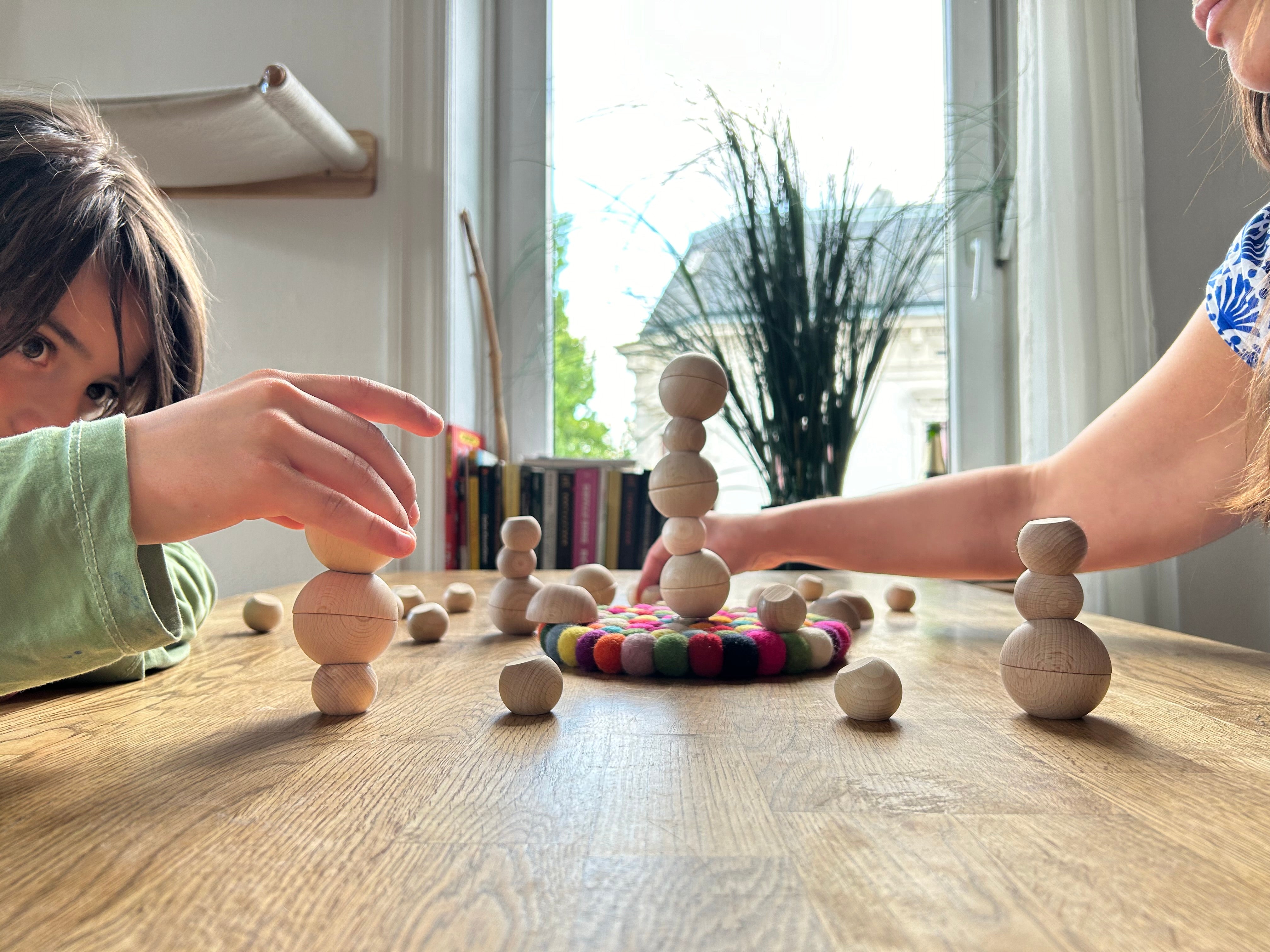Familie spielt gemeinsam mit einem Holz Stapelspiel und baut Ballance-Türme